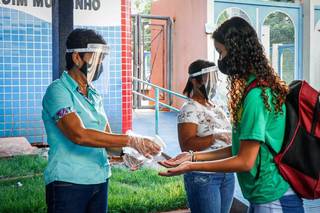 Estudante passando pelos procedimento de biossegurança para entrar em escola (Foto: Henrique Kawaminami/Arquivo)