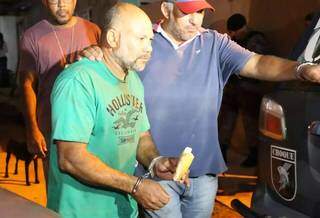 Cleber de Souza Carvalho, o &#34;Pedreiro Assassino&#34;, come pão enquanto é conduzido por policial durante diligências para achar corpos de suas vítimas. (Foto: Kísie Ainoã)