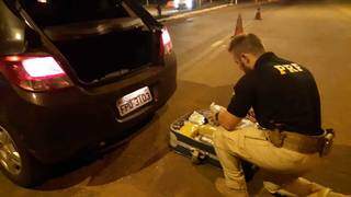 Policial retirando os tabletes de supermaconha da mala. (Foto: PRF)