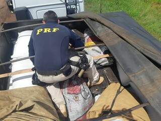 Policial retirando os tabletes de maconha da carga. (Foto: PRF) 