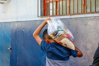 Jovem carrega cesta básica em Campo Grande (Foto: Henrique Kawaminami/Arquivo)
