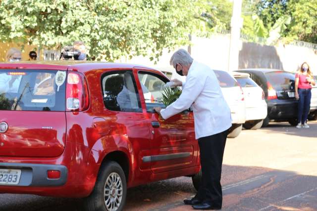 Com 35 litros de &aacute;gua benta, fi&eacute;is s&atilde;o ungidos em drive no Domingo de Ramos