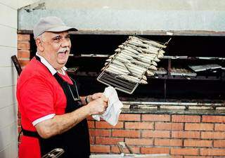 Seu Mauricio preparando uma sardinha assada na churrasqueira – receita de família (Foto: André Patroni)