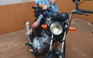 Um dos filhos do casal em cima da moto furtada. (Foto: Direto das Ruas)