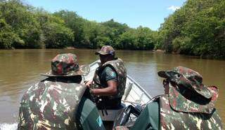 Três agentes da Polícia Militar Ambiental fiscalizando rio de barco. (Foto: Divulgação)