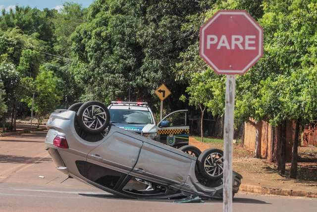 Carro bate em outro estacionado e capota em cruzamento 