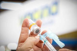 Profissional de saúde insere dose de vacina Coronavac na seringa para aplicar em pessoa (Foto: Henrique Kawaminami)