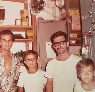 O pai de óculos junto aos dois filhos e o irmão na loja da rua 14 de Julho, em 1970 (Foto: Arquivo Pessoal)