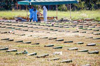 Profissionais de funerária sepultam pessoa no Cemitério Jardim da Paz, em Campo Grande, seguindo normas de biossegurança (Foto: Henrique Kawaminami)