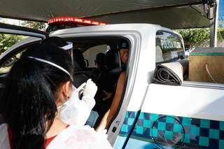 Policiais militares foram com viatura no drive-thru da Cassems receber a primeira dose da vacina contra a covid-19 (Foto Henrique Kawaminami)
