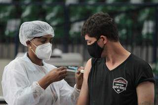 Profissional da saúde aplica dose do imunizante contra a covid-19, no Estádio do Guanandizão, em Campo Grande. (Foto: Marcos Maluf)