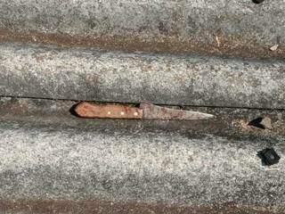 Com manchas de sangue, faca usada em tentativa de feminicídio foi encontrada no telhado da casa (Foto: Divulgação)