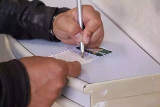 Apostador anotando números em talão da Mega-Sena. (Foto: Arquivo / Campo Grande News)