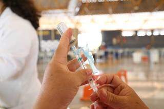 Profissional de saúde prepara dose em posto de vacinação de Campo Grande (Foto: Kísie Ainoã)