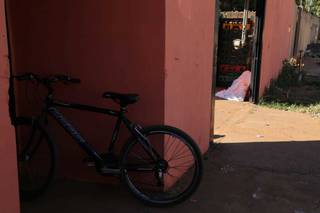 Bicicleta de Rafael da Silva Costa no local do crime. Aos fundos, o corpo dele coberto por lençol branco. (Foto: Kísie Ainoã)