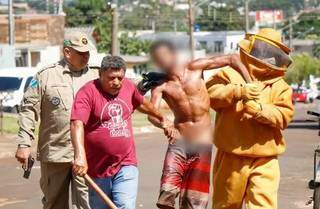 Morador (de camisa vermelha) e bombeiros tentam conter o suspeito (Foto: Henrique Kawaminami)
