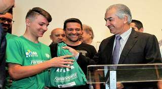 Kawãh recebendo do governador Reinaldo Azambuja kit do Bolsa Atleta. (Foto: Fundesporte)