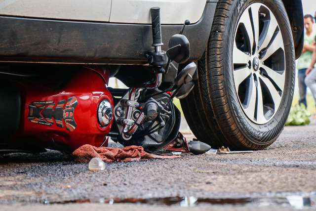 Moto vai parar embaixo de carro ap&oacute;s acidente em cruzamento