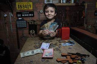 Joãozinho com notas de moedas estrangeiras e antigas que ganha dos clientes (Foto: Marcos Maluf)