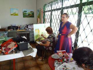 Na foto postada no Facebook, Catarina dando aulas de pintura para outras mulheres em casa.
