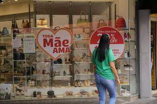 Mulher caminha em frente a loja com promoção do Dia das Mães (Foto: Kísie Ainoã/Arquivo)