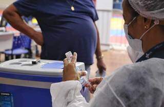 Profissional de saúde prepara injeção para vacinar pessoa no Guanandizão, em Campo Grande (Foto: Paulo Francis)