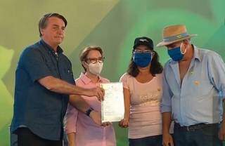 Bolsonaro e Tereza Cristina (à esquerda) entregam título para assentados. (Foto: Reprodução)