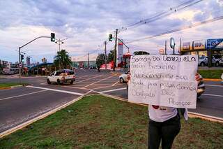 Mulher segura cartaz em cruzamento de Campo Grande, com pedido de ajuda. (Foto: Arquivo)