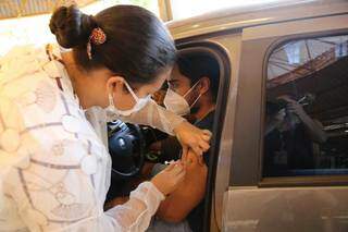 Profissional vacina rapaz em drive-thru da Capital (Foto: Kísie Ainoã)