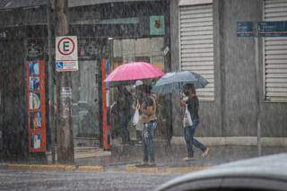 Mulheres tentanto atravessar a rua com a chuva desta manhã. (Foto: Henrique Kawaminami)