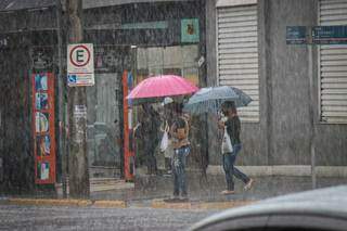 Mulheres tentanto atravessar a rua com a chuva desta manhã. (Foto: Henrique Kawaminami)