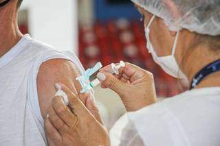 Servidor da saúde aplicando dose da vacina contra a covid-19 em ponto de imunização em Campo Grande. (Henrique Kawaminami)