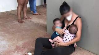 Mãe com dois bebês de colo sentada no chão na fila da vacina. (Foto: Direto das Ruas)