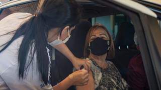 Mulher é vacinada em drive-thru montado na Capital (Foto: PMCG)