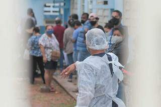 Profissional organiza fila para exames de covid em posto de saúde da Capital. (Foto: Marcos Maluf)