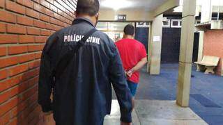 Universitário preso em Dourados é conduzido por policial em delegacia (Foto: Adilson Domingos)