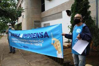 Vestidos de azul e com faixas da campanha nacional, profissionais da imprensa e integrante do Sindjor se reuniram em frente ao prédio da SES (Foto: Saul Schramm)