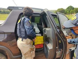 Policiais diante da carga de maconha encontrada no veículo. (Foto: PRF) 