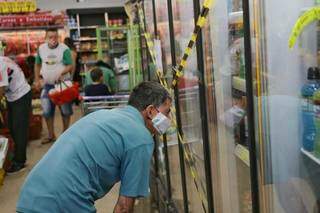 Cliente &#39;checando&#39; produtos em geladeira, lacrada pois a venda de cerveja gelada está proibida nos supermercados (Foto: Paulo Francis)