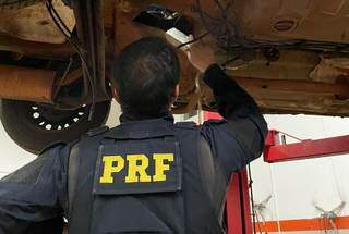 Policial retira tablete de pasta-base de assoalho de carro (Foto: Divulgação/PRF)