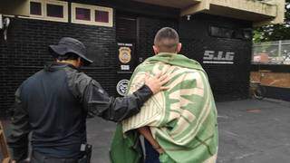 Enrolado em cobertor, preso por tráfico é conduzido por agente do SIG (Foto: Adilson Domingos)