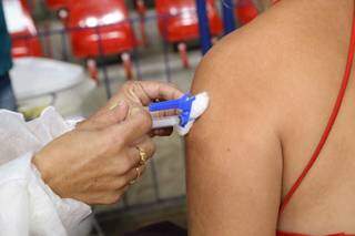 Profissional de saúde aplica vacina em braço de mulher (Foto: Kísie Ainoã)