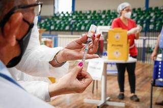 Dose da vacina contra a covid-19 nas mãos de uma servidora da saúde. (Foto: Henrique Kawaminami)