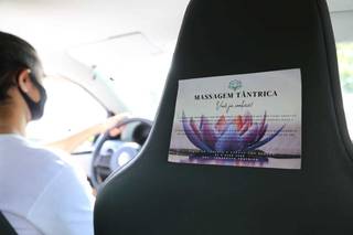 Luiz dirigindo seu carro com propaganda da massagem tântrica colada no banco do passageiro (Foto: Kísie Ainoã)