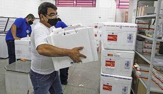 Funcionários manipulam caixas térmicas contendo vacinas em central de distribuição (Foto: Governo de MS/Divulgação)
