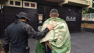 Enrolado em cobertor com logo de time, preso por tráfico é conduzido por agente do SIG de Dourados (Foto: Adilson Domingos)
