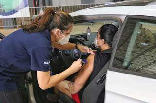 Mulher sendo vacinada contra covid-19 em drive-thru de Campo Grande. (Foto: Paulo Francis)