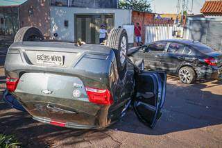 Motorista bate na traseira de carro estacionado e capota em avenida 