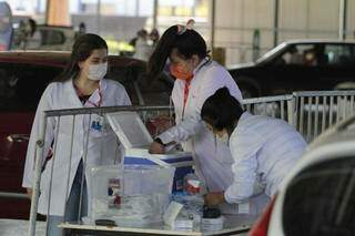 Profissionais de saúde preparam doses da vacina em drive-thru na Capital (Foto: Marcos Maluf)