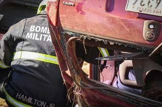 Bombeiro observa vítima dentro de carro capotado (Foto: Henrique Kawaminami)